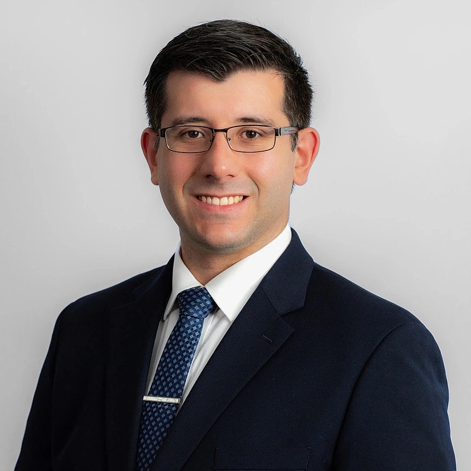Smiling man in suit against plain background.