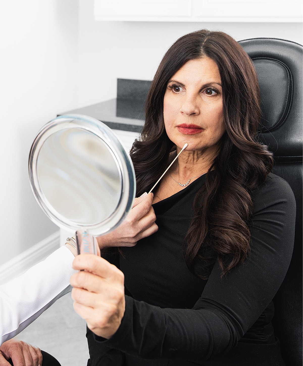 Woman examining her reflection in a cosmetic setting.