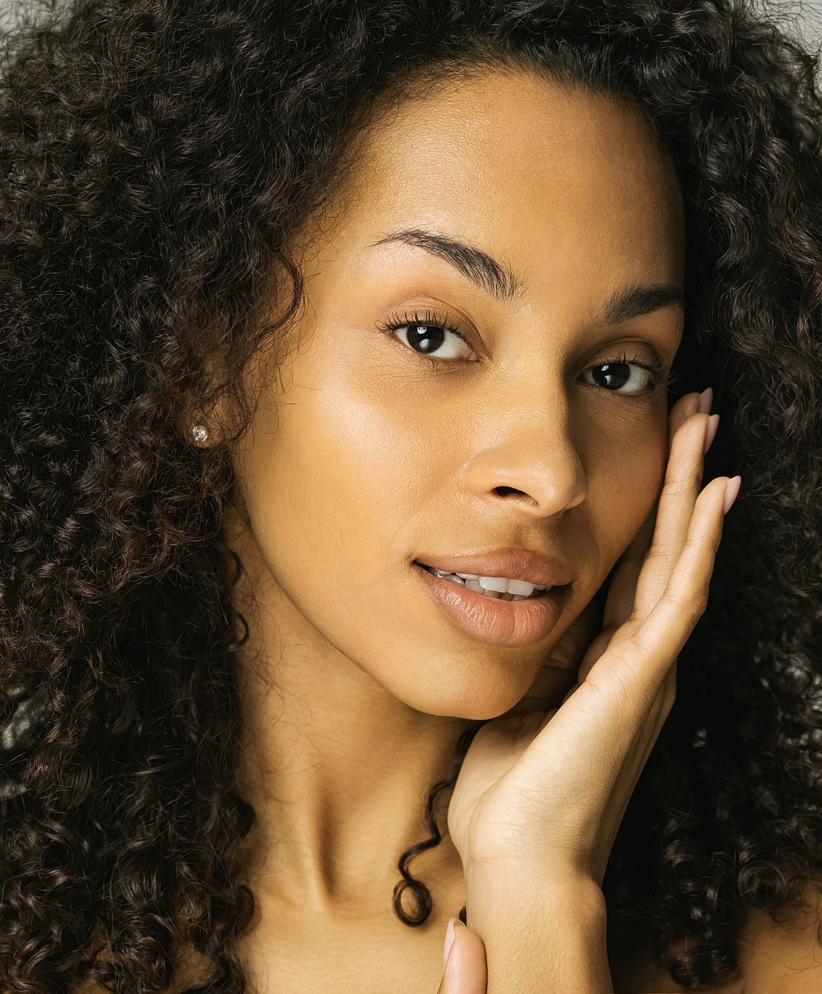 Woman with curly hair and natural makeup.