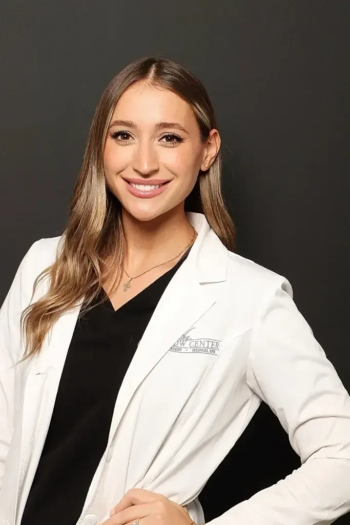 Smiling professional in white coat against black background.