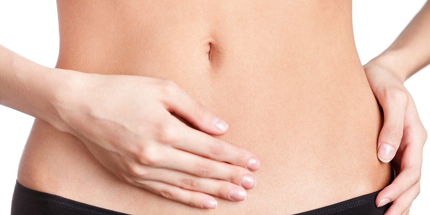 Woman's hands on flat abdomen with gentle touch.