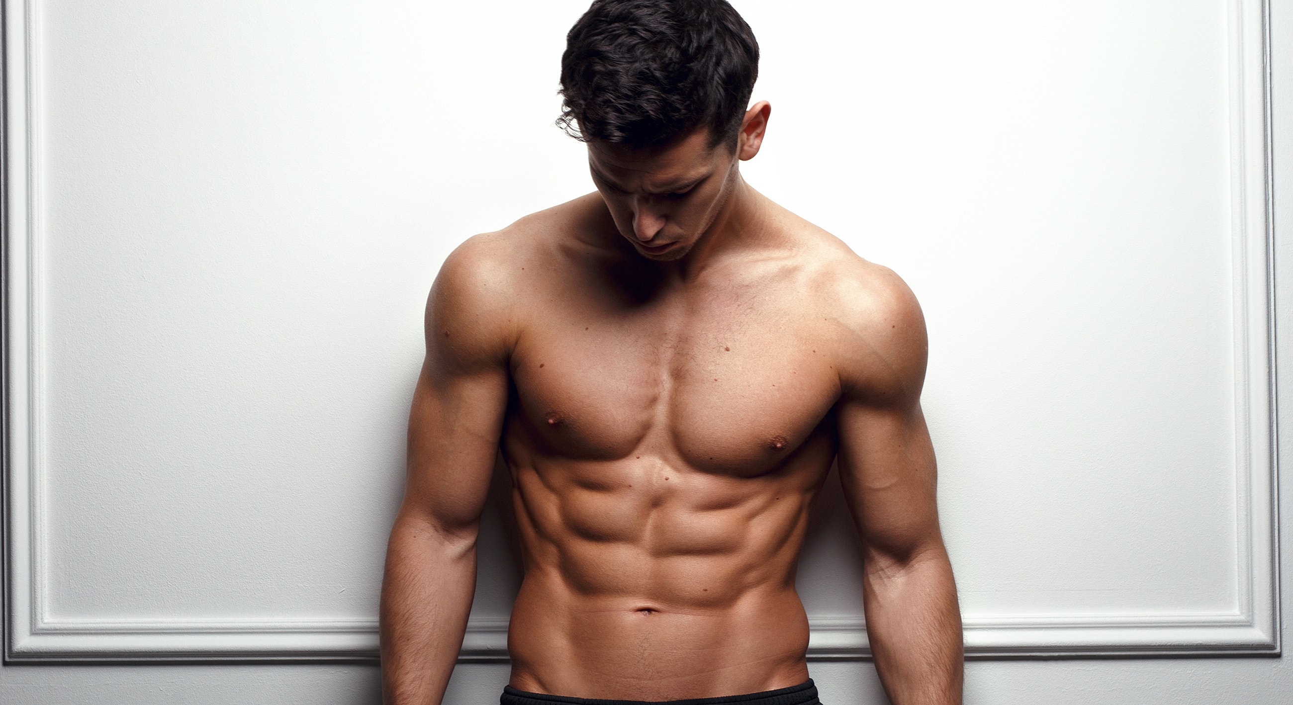 Muscular man with defined abs against white background.