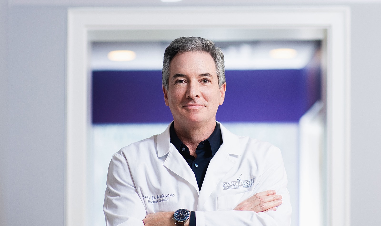 Paramus plastic surgery doctor in white coat, smiling confidently.