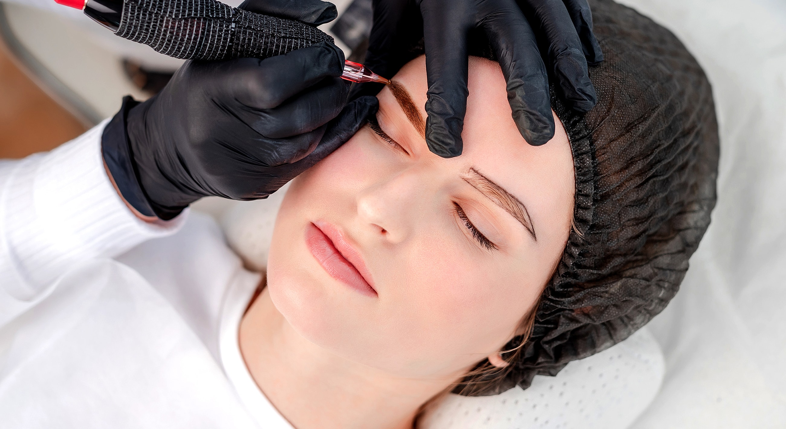 Woman receiving eyebrow tattooing procedure.