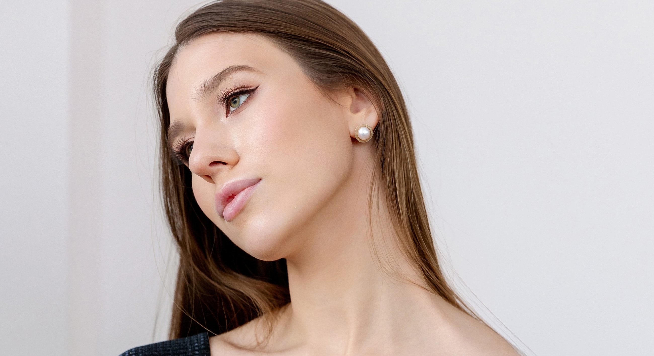 Model with long hair and pearl earrings.