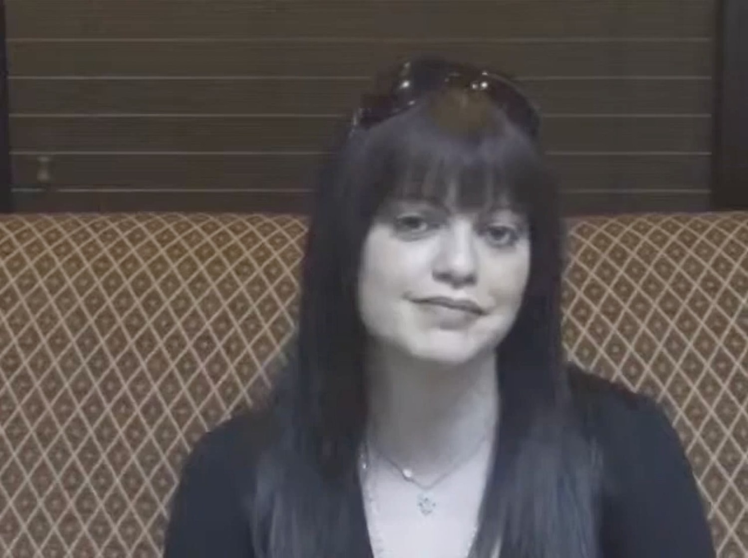 Person sitting on a patterned couch indoors.