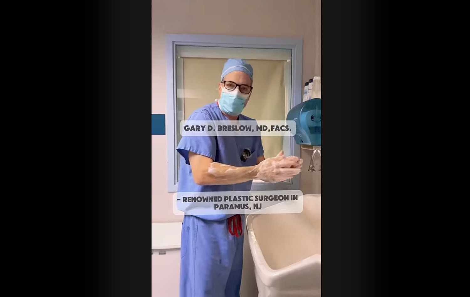 Surgeon washing hands in medical setting.
